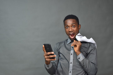 young black man in medical field, holding a white coat using a mobile phone smiling