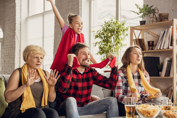 Excited, happy big family watching football, soccer, basketball, hockey, tennis, rugby match on the couch at home. Fans emotional cheering for favourite national team. Sport, TV, championship.