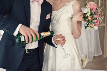 The groom pours an alcoholic drink into a champagne glass. Newlyweds at a wedding party.