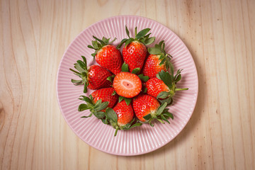 Strawberries in a pink plate on wooden table