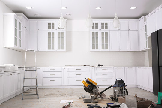 Renovated kitchen interior with stylish furniture, refrigerator and maintenance equipment