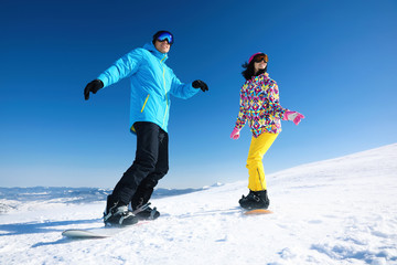 Fototapeta na wymiar Couple snowboarding on snowy hill. Winter vacation