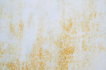 White old metal sheet with small spots of rust. The rust comes out through the paint with non-uniform spots. White background with brown corrosion.