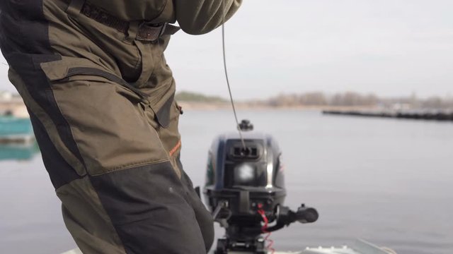 Fisherman starts outboard motor before fishing trip