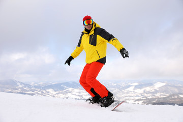 Fototapeta na wymiar Male snowboarder on snowy hill. Winter vacation