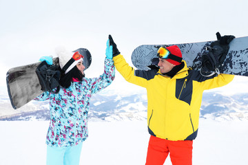 Lovely couple with snowboards on hill. Winter vacation