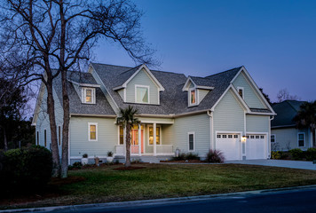 offset view of beautiful luxury home at dusk with lights.