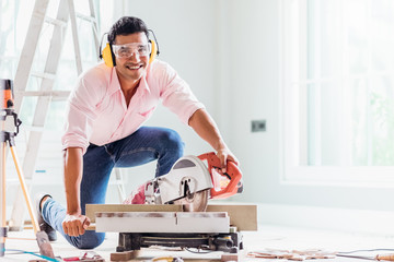 Smart indian contractor hand using sawing machine wood work and working overall equals a wooden bar...
