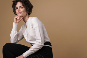 Image of pleased beautiful woman looking at camera while sitting
