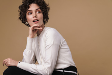 Image of surprised beautiful woman looking aside while sitting