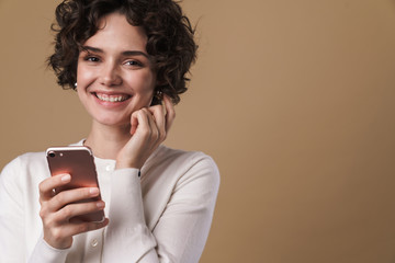 Fototapeta premium Image of cheerful beautiful woman using cellphone and smiling