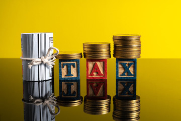 TAX letter and stacking coins with financial concept. Image in low light view.