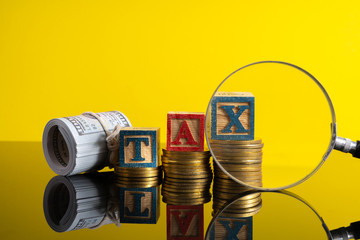 Magnifier glass and stacking coins and tax letter cube with low light view.