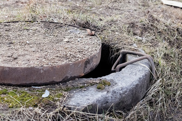 Old open concrete well among yellow grass