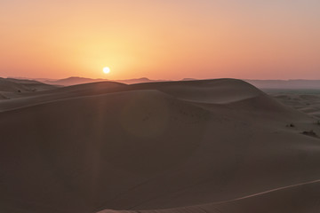 Fototapeta na wymiar Orange sunset on the sahara desert in Morocco during chilly spring time. Plenty of warm colors.