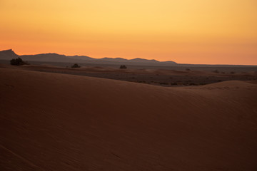 Fototapeta na wymiar Beautiful, orange, early sunrise on the erg chebbi, sahara desert in Marzouga, Morocco.