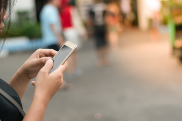 Close up A woman using a smartphone Walking on the street with many people. On a sunny day