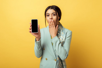 Naklejka premium beautiful african american girl covering face and holding smartphone with blank screen on yellow