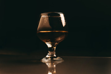 glass of cognac on a dark background with a warm filter close up