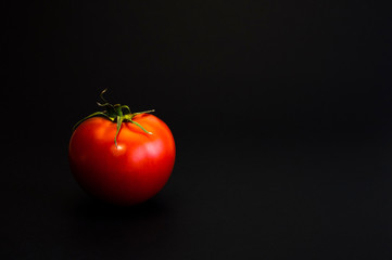 Red tomato. With a green spine. On a black background.