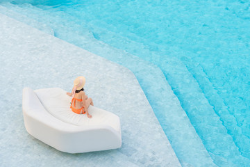 Top view of Asian woman wearing sexy orange swimsuits with hat leisure and relaxing lounging on white outdoor sofa sun bed lounger at the big swimming pool. Summer vacation concept.