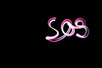 handwritten word SOS, light painting experiment with bulb exposure, at night
