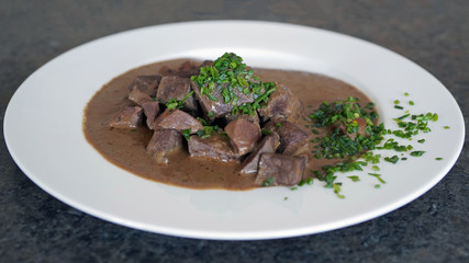 ready to eat, liver, heart and kidneys in sour sauce with chives on a white plate