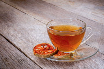 Bael fruit juice or quince tea and dried bael sliced fruit (Aegle marmelos or wood golden apple) isolated on old rustic wood table background. Healthy drinks concept. Vintage tone .