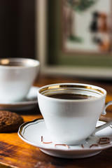 two white cups with coffee and oat cookies on a wooden table