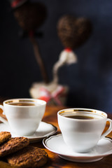two white cups and oatmeal cookies on a wooden table
