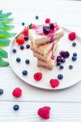 Slice of classic cheesecake with fresh berries on the white plate - healthy organic summer dessert.