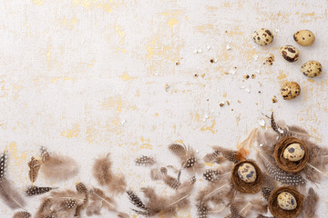 Obraz premium Composition with quail eggs and feathers on gold abstract background. Spring, easter concept. Flat lay, top view, copy space.