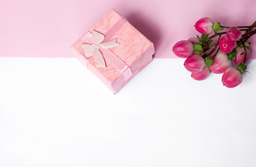 a bouquet of flowers and a gift box on a pink and white background, greeting card template for March 8, mother's day and birthday, copyspace for text