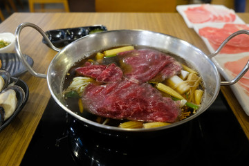 Cooking food by put a flesh beef and vegetable in to a hot pot