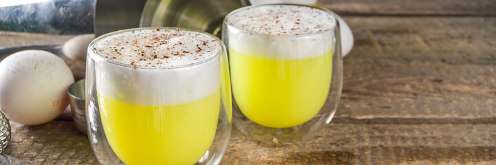 Autumn Homemade Bourbon Egg Flip Cocktail with spices, wooden background with ingredients