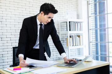 Happy of successful asian young businessman have stressed see a the document business plan and laptop computer on wooden table In the office room background.