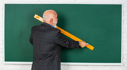 senior man teacher use ruler while drawing. bearded tutor man draw with ruler on blackboard. back to school. school disciplines. Education and knowledge. geometric shapes at high school