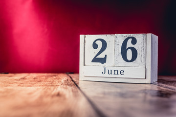 June 26th. Day 26 of month, calendar on business office table, workplace with vivid maroon red background. Summer time