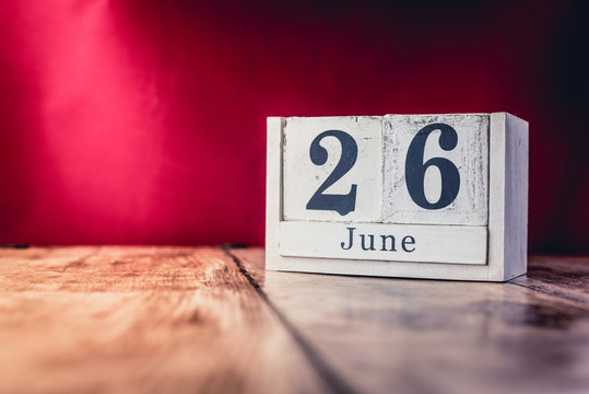 June 26th. Day 26 of month, calendar on business office table, workplace with vivid maroon red background. Summer time