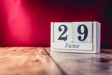 June 29th. Day 29 of month, calendar on business office table, workplace with vivid maroon red background. Summer time