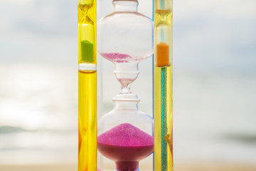 The hourglass passing time on the beach The hourglass in front of the bright blue sky with white...
