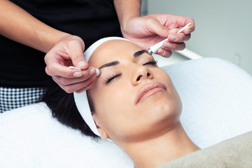 Cosmetologist making the eyes contour therapy for rejuvenation to woman on the spa center.