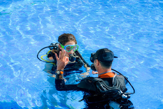 beautiful young woman taking a scuba diving lesson in swimming pool