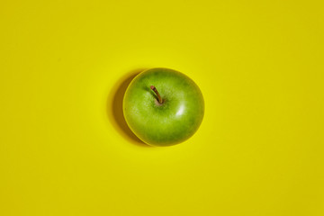 Green apple on yellow background. Flat lay, top view, copy space . Food dietary concept.