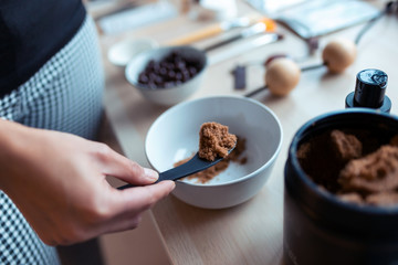 A young woman preparing chocolate cream with natural ingredients for body treatment. Body care concept.