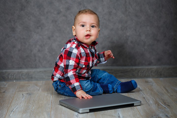 Naklejka premium Little kid in shirt plays with laptop