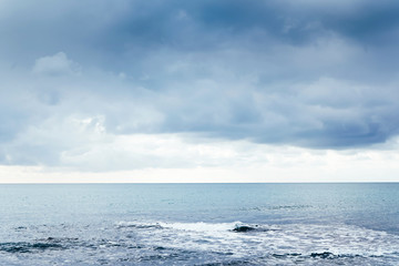 Naklejka na ściany i meble Seascape. Clouds float across the sky, a wave foams into the sea