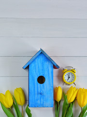 yellow tulips,yellow alarm clock and a bright blue birdhouse on a pink background. Spring mood. Spring card.picture for packages