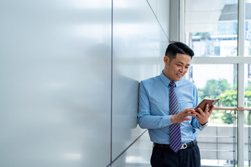  Smiling businessman using cell phone near glass window stock photo
