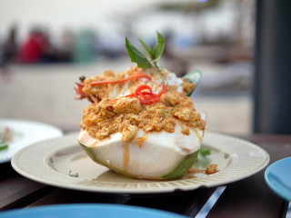 Prawns, clams, crabs, fish steamed spicy Thai with curry paste, served in coconut milk, Homok with coconut meat and seafood, put on a white plate at the restaurant by the sea Blurred image